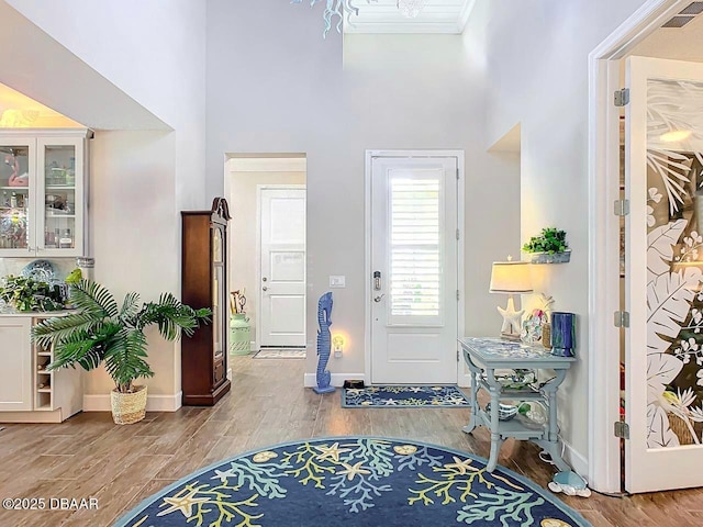 entryway with visible vents, wood finished floors, and ornamental molding