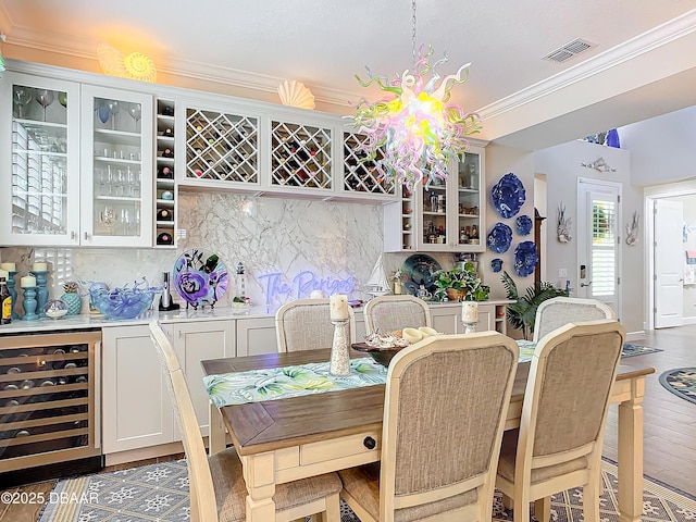 dining area featuring beverage cooler, dark wood-type flooring, visible vents, a dry bar, and crown molding