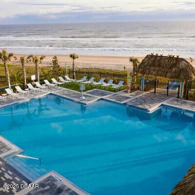 pool with a beach view, a water view, and fence