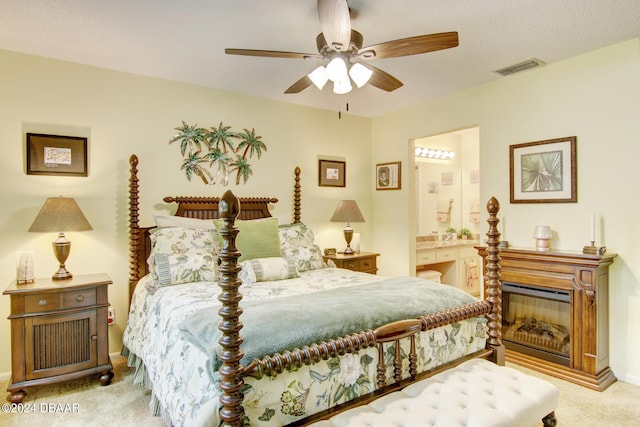 bedroom with ceiling fan, connected bathroom, a textured ceiling, and light carpet