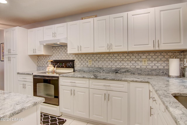 kitchen with backsplash, white cabinets, light tile patterned floors, light stone countertops, and electric range