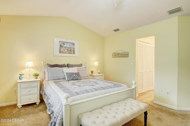 bedroom with a closet, vaulted ceiling, and light colored carpet