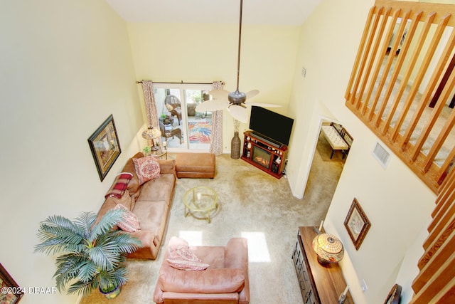 living room with ceiling fan, a high ceiling, and carpet flooring