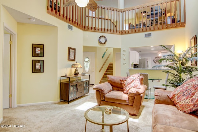 living room featuring ceiling fan, light carpet, and a towering ceiling