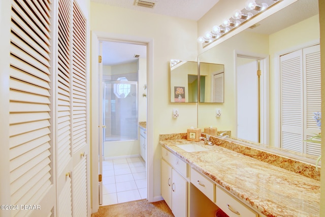 bathroom featuring enclosed tub / shower combo, vanity, and tile patterned flooring