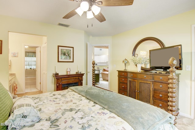 tiled bedroom featuring ceiling fan and ensuite bath