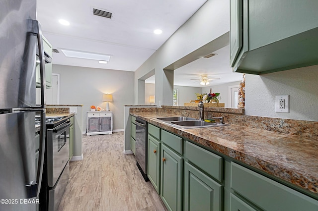 kitchen with green cabinetry, appliances with stainless steel finishes, kitchen peninsula, and sink