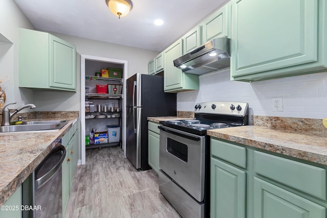 kitchen featuring sink, tasteful backsplash, light hardwood / wood-style flooring, appliances with stainless steel finishes, and green cabinets