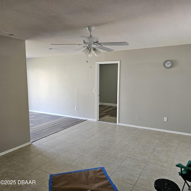 tiled spare room with ceiling fan and a textured ceiling