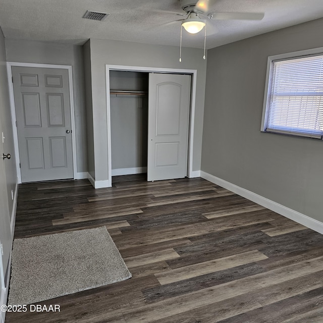 unfurnished bedroom featuring ceiling fan, dark hardwood / wood-style floors, a textured ceiling, and a closet