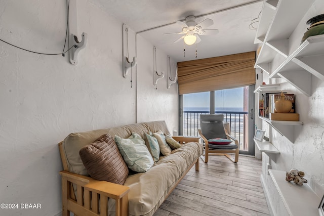 living room with light hardwood / wood-style floors, a water view, and ceiling fan