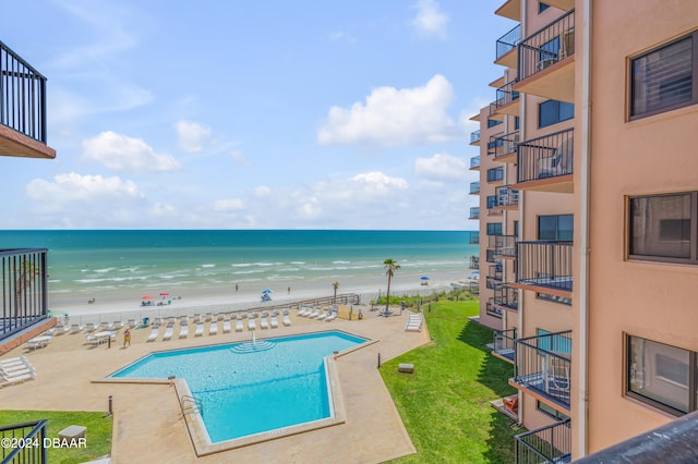 view of pool featuring a lawn, a beach view, a water view, and a patio area