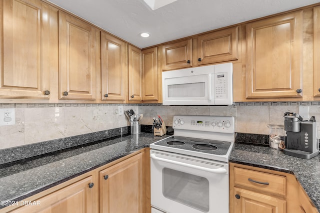 kitchen featuring dark stone counters, white appliances, and decorative backsplash