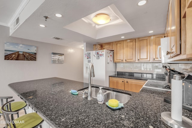 kitchen featuring tasteful backsplash, dark stone counters, white appliances, a breakfast bar, and kitchen peninsula