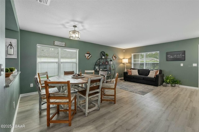 dining space with light hardwood / wood-style flooring and a textured ceiling