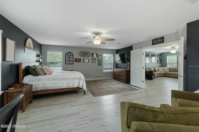 bedroom with multiple windows, ceiling fan, and light wood-type flooring