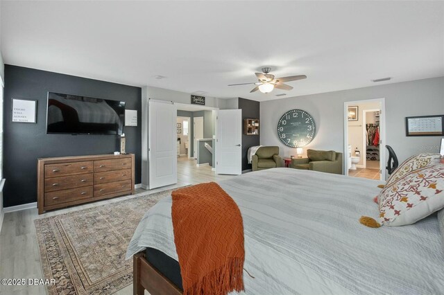 bedroom featuring a spacious closet, a closet, ceiling fan, and light wood-type flooring