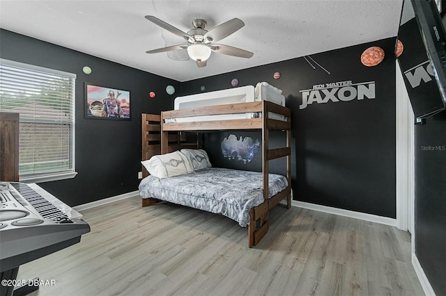 bedroom with hardwood / wood-style floors, ceiling fan, and a textured ceiling