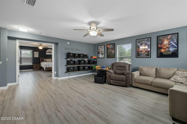 living room with a wealth of natural light, ceiling fan, and light wood-type flooring