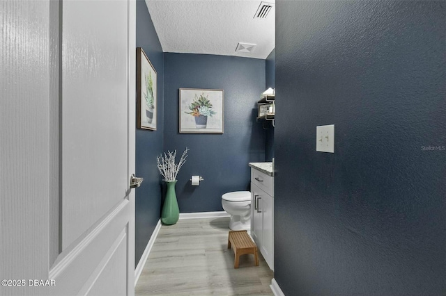 bathroom featuring vanity, toilet, wood-type flooring, and a textured ceiling