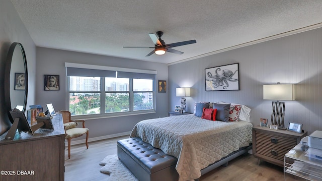 bedroom with ornamental molding, a textured ceiling, ceiling fan, and light hardwood / wood-style flooring