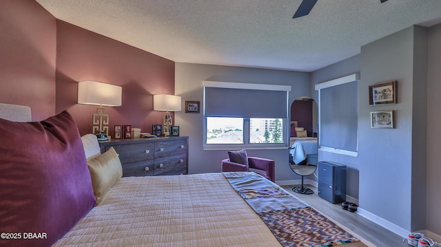 bedroom with ceiling fan, light hardwood / wood-style floors, and a textured ceiling