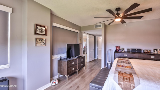 bedroom with light wood-type flooring, a textured ceiling, and ceiling fan