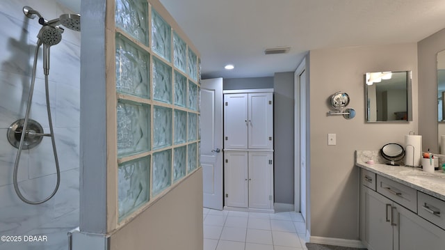 bathroom featuring vanity, tile patterned flooring, and tiled shower