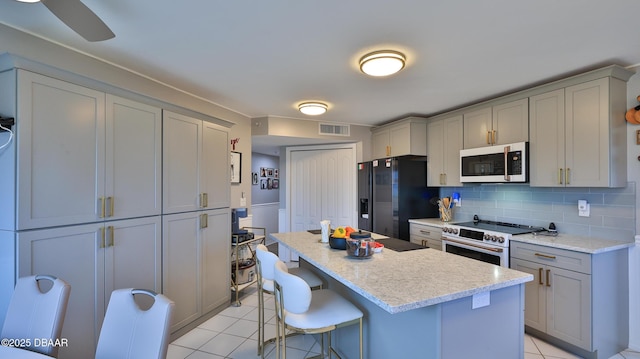 kitchen with gray cabinets, tasteful backsplash, light tile patterned flooring, and white appliances