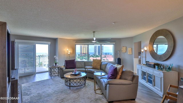 living room featuring ceiling fan, a healthy amount of sunlight, hardwood / wood-style floors, and a textured ceiling