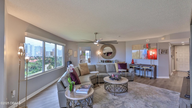 living room featuring hardwood / wood-style flooring, ceiling fan, and a textured ceiling