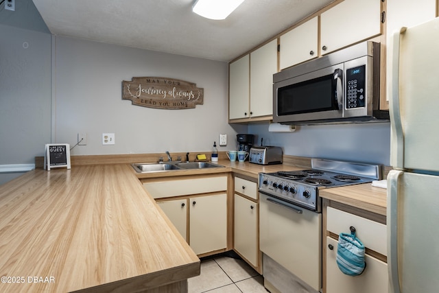 kitchen with light tile patterned flooring, sink, white cabinets, and white appliances