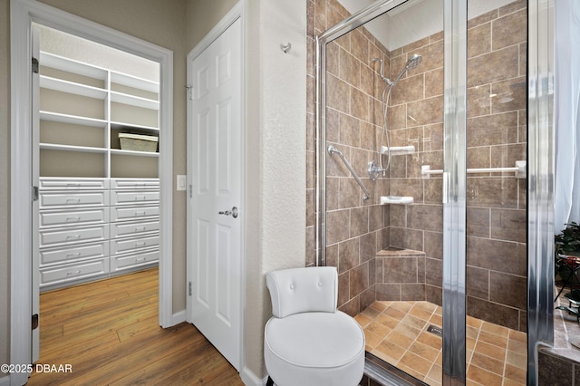 bathroom with wood-type flooring, toilet, and a shower with door