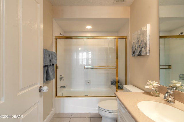 full bathroom with toilet, bath / shower combo with glass door, vanity, and tile patterned floors