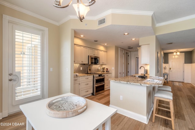 kitchen featuring stainless steel appliances, light hardwood / wood-style floors, light stone counters, kitchen peninsula, and a textured ceiling