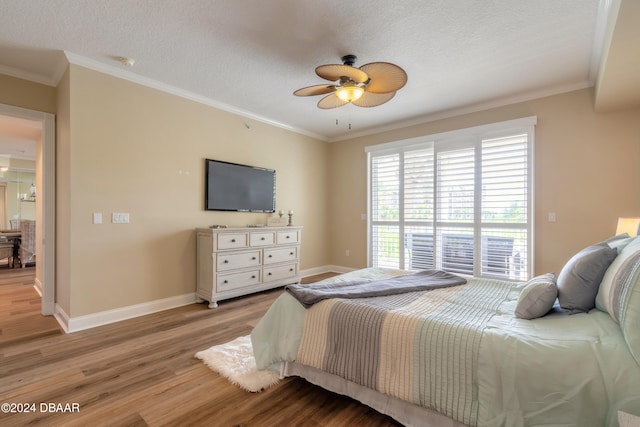 bedroom featuring a textured ceiling, light wood-type flooring, ceiling fan, and crown molding