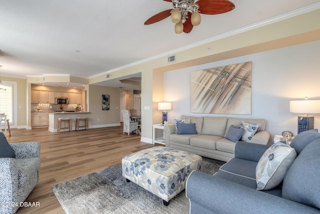 living room featuring ceiling fan, light hardwood / wood-style flooring, and crown molding