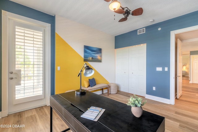 home office featuring wood-type flooring, a textured ceiling, and ceiling fan