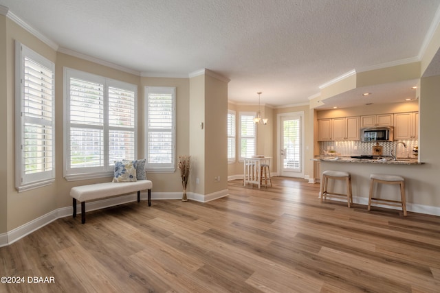 interior space featuring a kitchen bar, light wood-type flooring, a wealth of natural light, and light stone counters