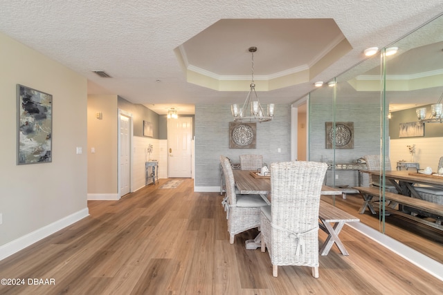 dining space featuring a textured ceiling, hardwood / wood-style flooring, and a raised ceiling