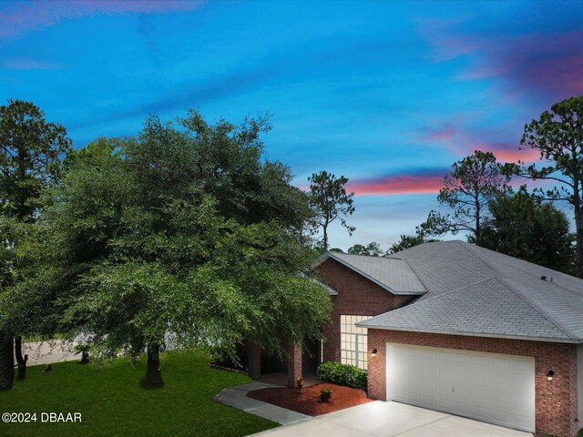 view of front of home with a garage and a lawn