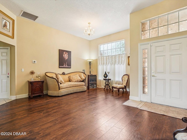 entryway with dark wood-type flooring, a chandelier, and a textured ceiling