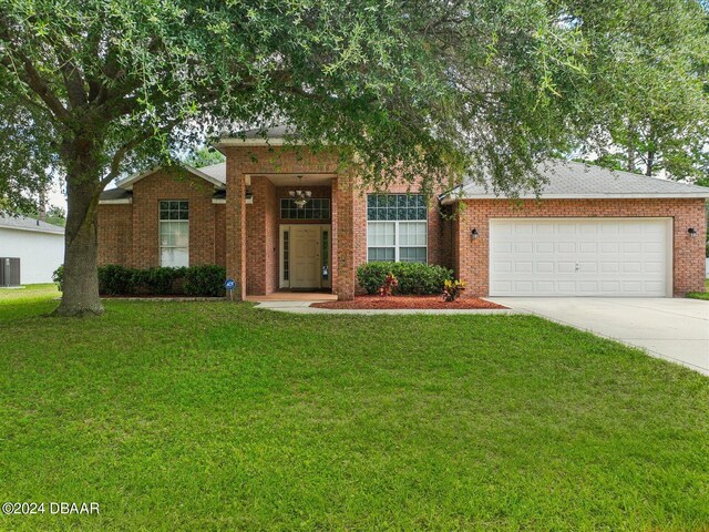 view of front facade featuring a front lawn, a garage, and central AC unit