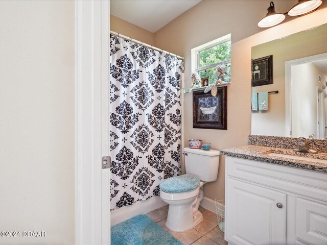 bathroom with toilet, curtained shower, vanity, and tile patterned floors