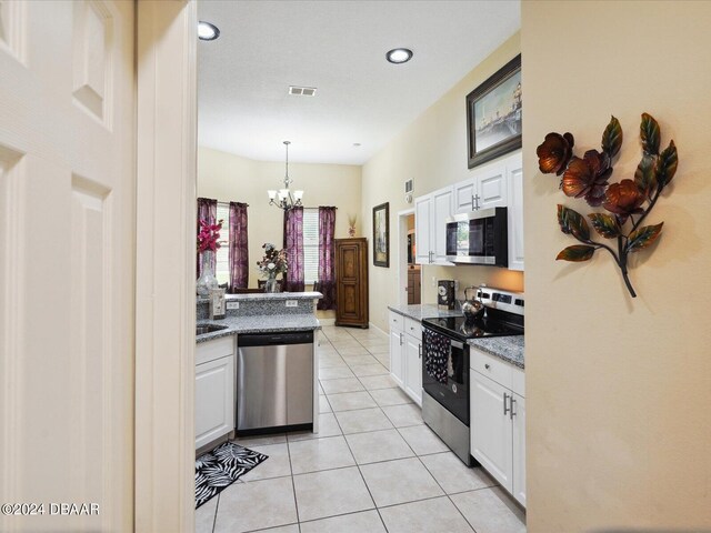 kitchen with white cabinets, a chandelier, light tile patterned flooring, appliances with stainless steel finishes, and decorative light fixtures