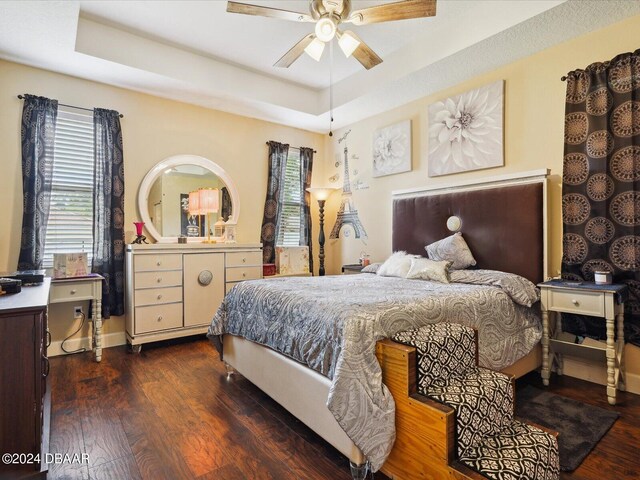 bedroom featuring ceiling fan, dark hardwood / wood-style floors, and a raised ceiling