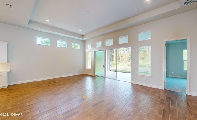 unfurnished living room with a raised ceiling and light hardwood / wood-style floors