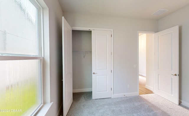 unfurnished bedroom featuring light carpet and a closet