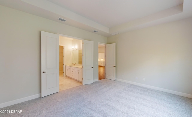 unfurnished bedroom with ensuite bathroom and light colored carpet