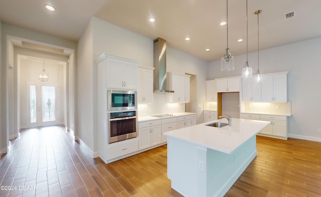 kitchen featuring appliances with stainless steel finishes, white cabinetry, and wall chimney range hood